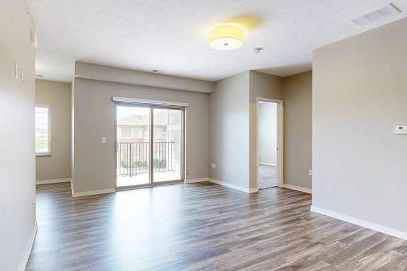 A living room with hardwood-style flooring and a sliding glass door to a balcony.
