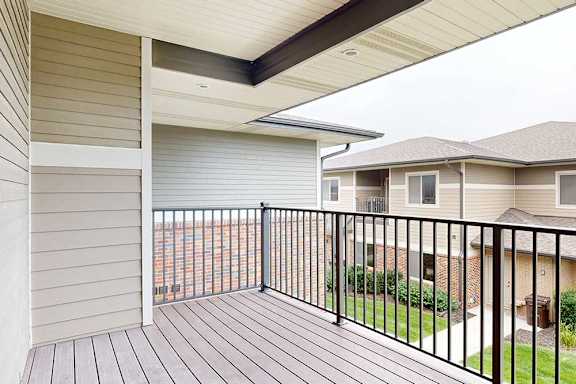 A spacious balcony with a black metal railing and a view of the neighborhood.