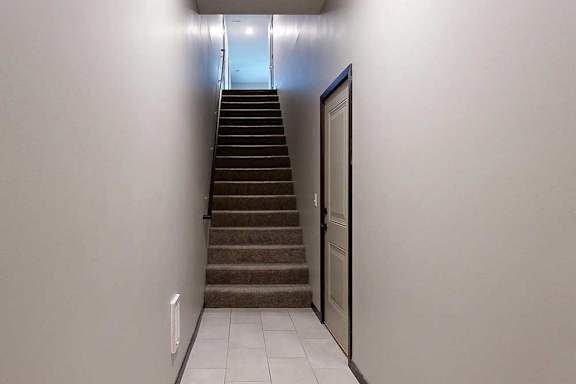 An entryway with a closed door to the attached garage, and a stairway leading up to the living area.