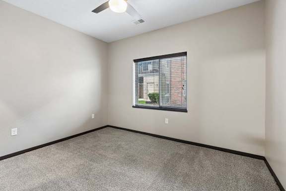 Empty bedroom with plush carpet, neutral finishes, and a large window providing natural light and exterior views.