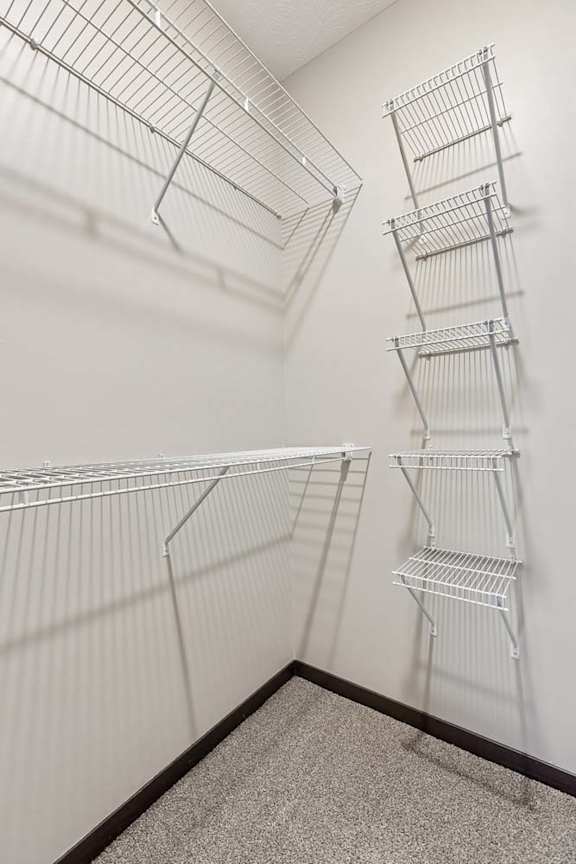 Walk-in closet with white wire shelving, carpeted flooring, and ample storage space for apartment living.