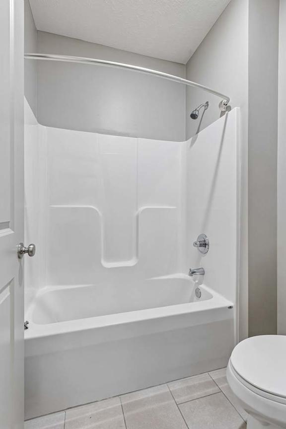 Bathroom with white tub-shower combination, built-in surround, and neutral walls for a clean, bright look.