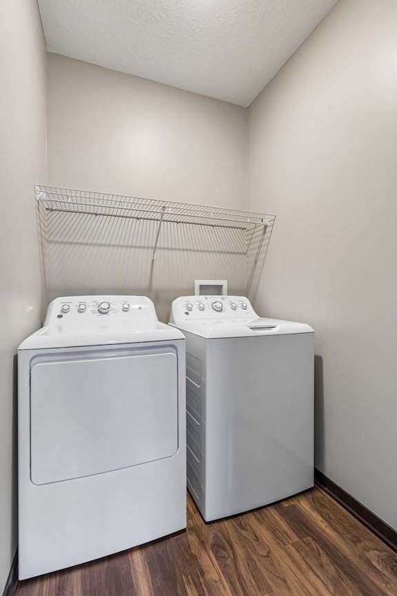 Laundry room with side-by-side washer and dryer, wire shelf storage, and neutral walls in an apartment home.