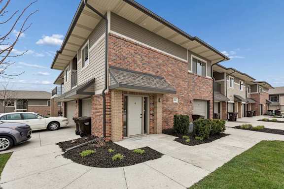 A residential building with a brick facade and a white car parked in front.