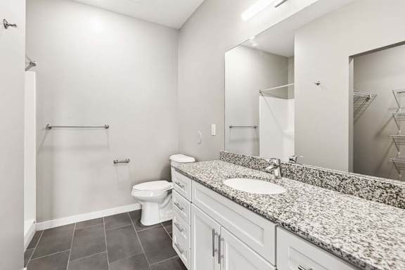 A bathroom with a toilet, sink, and mirror.