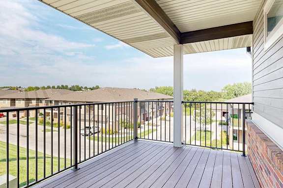 A spacious balcony with a black metal railing and a view of the neighborhood.