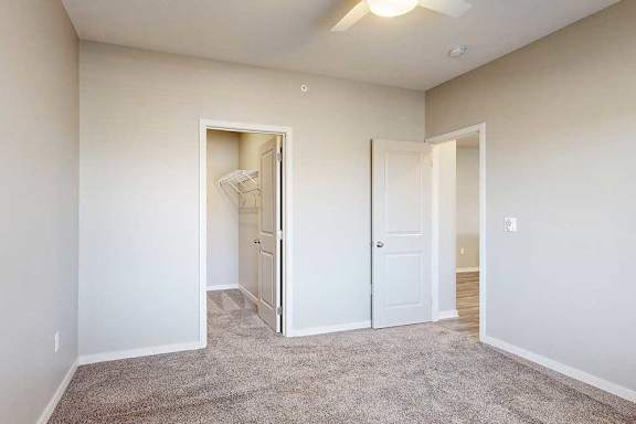 A room with a carpeted floor and two doors, one of which is open.