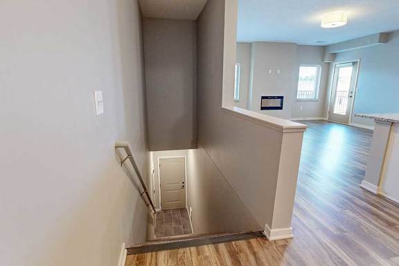 A stairway with a handrail leading down to the front entryway.