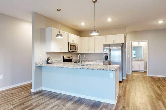A kitchen with white wooden cabinets, granite countertops, stainless steel appliances, and a peninsula countertop.