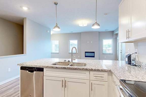 A kitchen peninsula with a double basin sink in front of a living room.