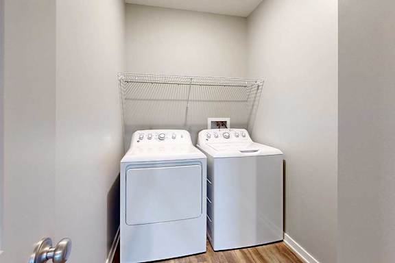 A side-by-side washer and dryer in a laundry room with overhead shelving.