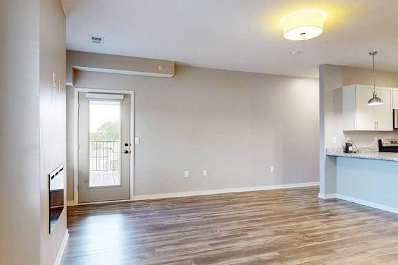A room with a door leading outside and a kitchen area with a counter and a sink.