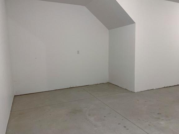 A white room with a concrete floor and a white wall.