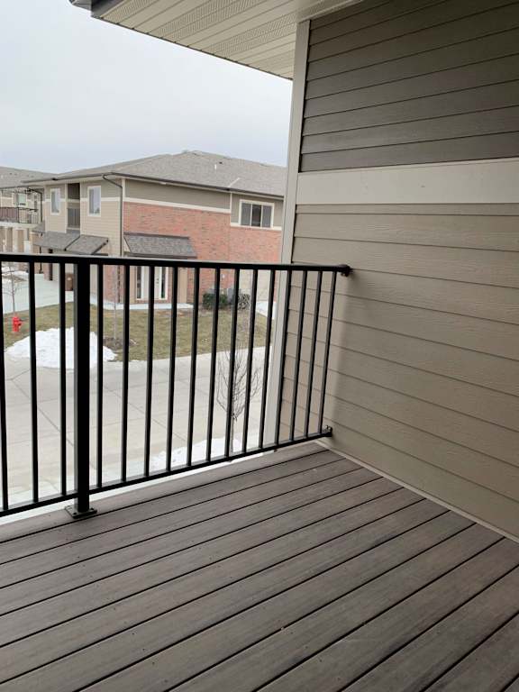 A balcony with a black railing and wooden floor.