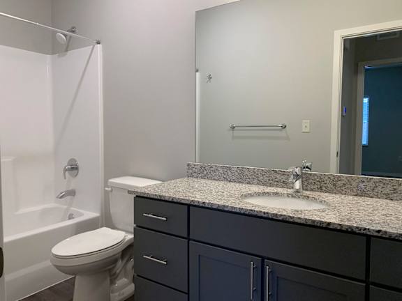 A bathroom with a white toilet and a granite counter top.
