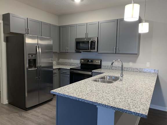 Kitchen with slate gray cabinets and matching stainless steel appliances at The Villas at Mahoney Park