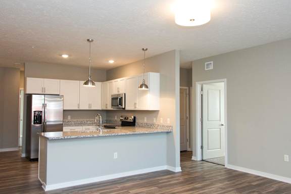 A kitchen with a refrigerator, microwave, and sink.