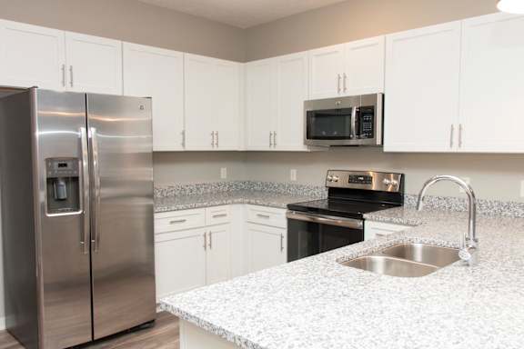 A kitchen with a stainless steel refrigerator and a granite countertop.