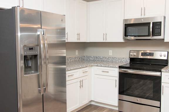 A kitchen with a stainless steel refrigerator, microwave, and oven.