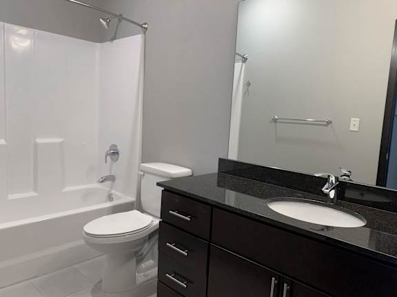 A bathroom with a white toilet and a black counter top.
