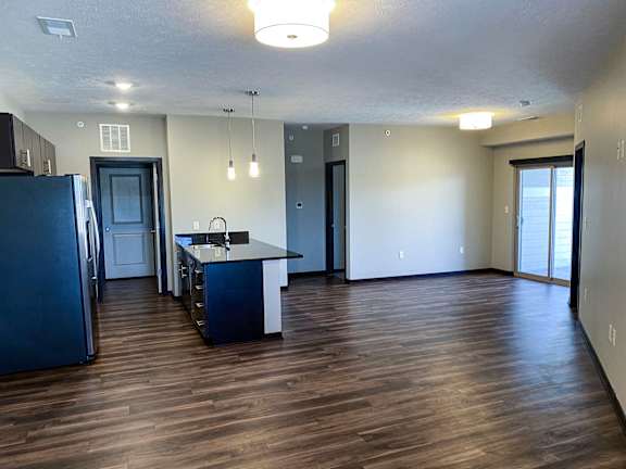 A kitchen with a refrigerator, sink, and cabinets.