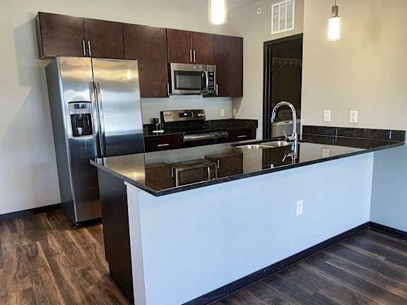 A kitchen with a refrigerator, microwave, and stove.