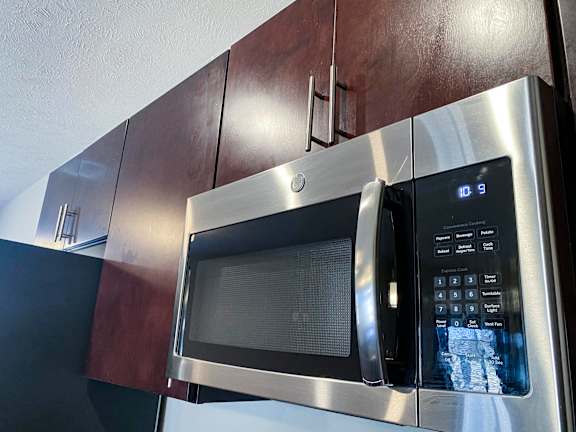 A stainless steel microwave with digital display and control panel.