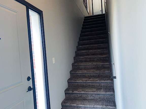 A staircase with a carpeted runner and a black handrail.
