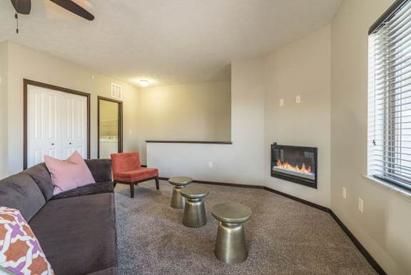 A living room with a grey couch, a red chair, and a fireplace.