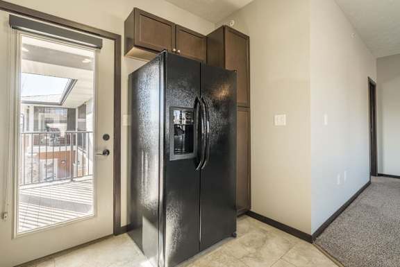 A black refrigerator is in a kitchen with a white door.
