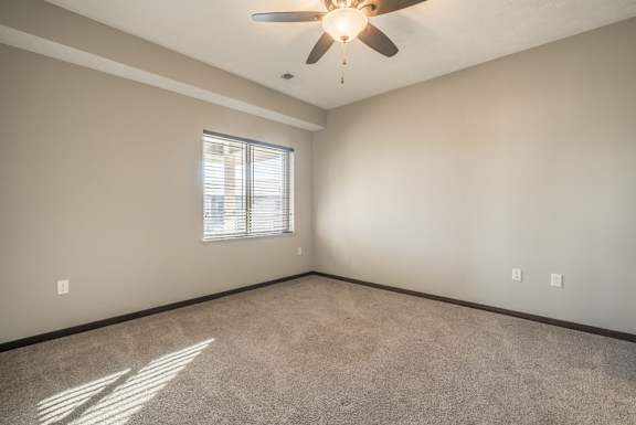 A room with a ceiling fan and a window with blinds.
