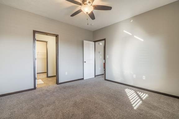 A room with a ceiling fan and carpeted floor.