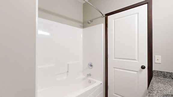 a white shower and tub in a bathroom with granite countertops