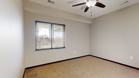 a bedroom with a window to the balcony and a ceiling fan