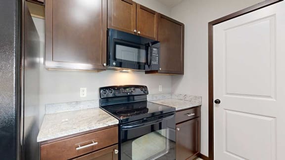 a kitchen with a black stove and microwave and wooden cabinets