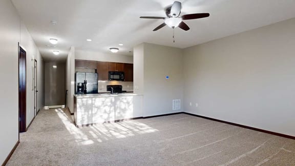 spacious living area with carpeted flooring, a ceiling fan, and natural light streaming in from nearby windows