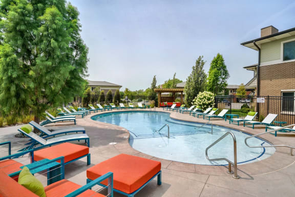 Organically shaped resort style pool surrounded a pool deck with bright blue lounge chairs