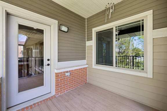 A white door is open to a balcony with a brick pillar.
