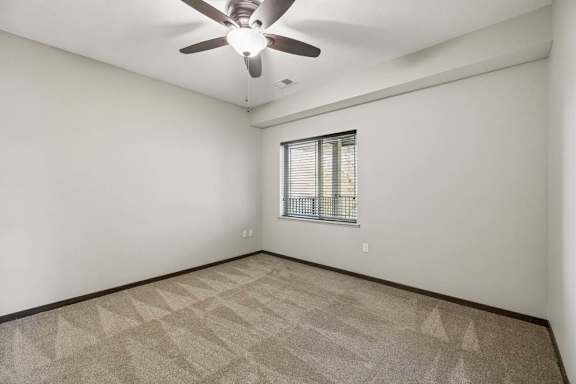 A room with a ceiling fan and a window with blinds.