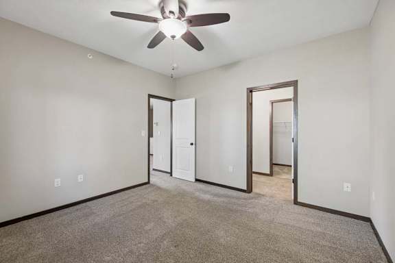 A room with a ceiling fan and carpeted floor.