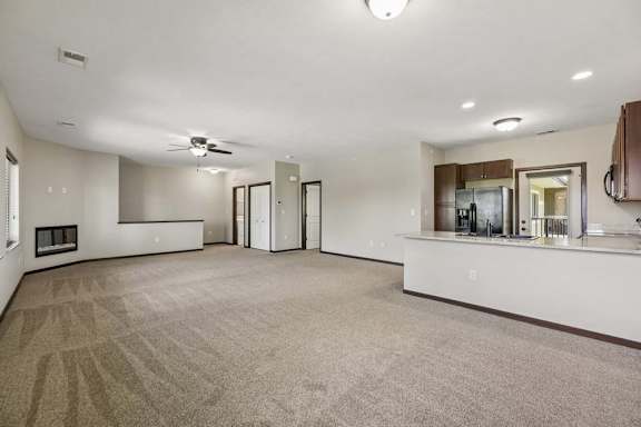 A spacious living room with a fireplace and a kitchenette in the background.