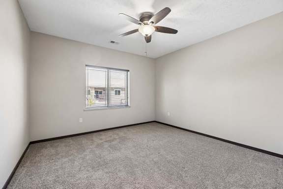 A room with a ceiling fan and a window with blinds.