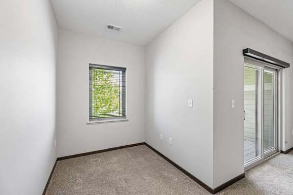 Small carpeted nook with tall wall, window with blinds, and sliding glass door nearby.