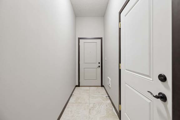 A hallway with a white door and a black door.