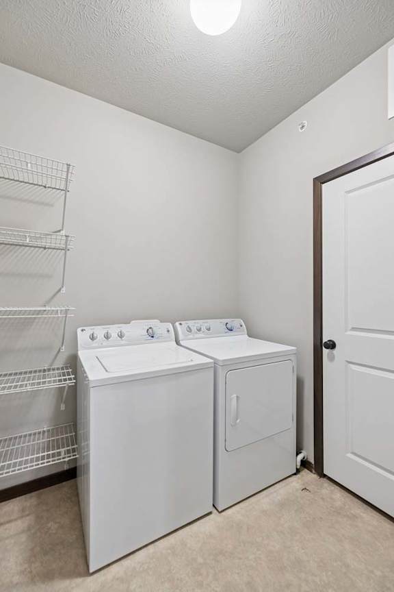In-home laundry room with white washer and dryer, wire shelving, neutral walls, and tile flooring.