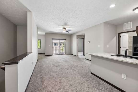 A spacious living room with a ceiling fan and sliding glass doors.