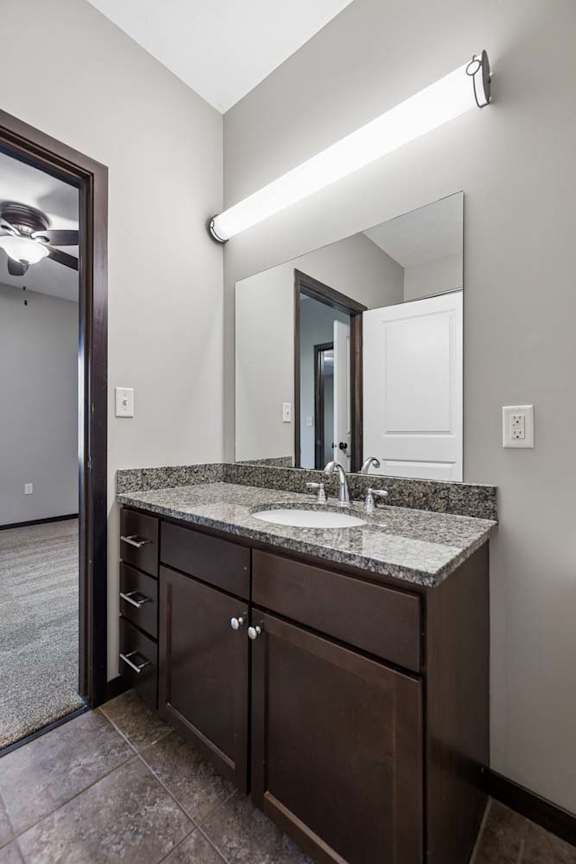 A bathroom with a sink, mirror, and brown cabinetry.