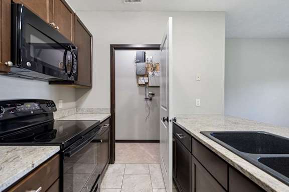 A kitchen with a black microwave above a black stove and a black sink.