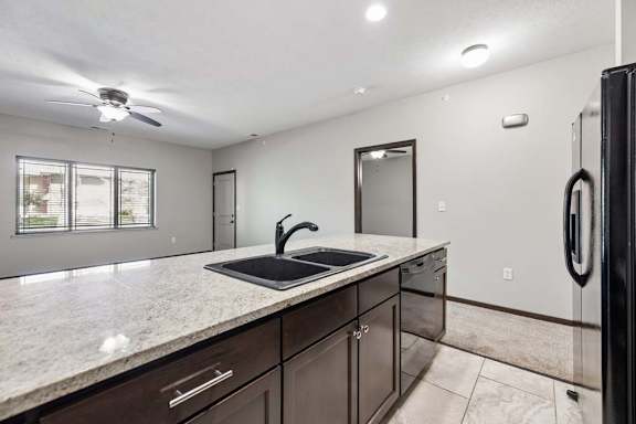 A kitchen with a sink, a refrigerator, and a ceiling fan.