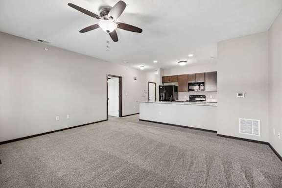 A spacious room with a ceiling fan and carpeted floor.